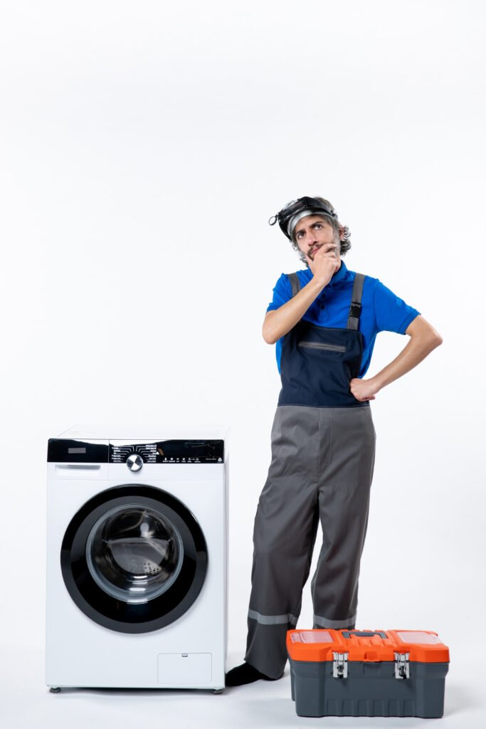 front view thinking repairman standing near washing machine tools bag white wall